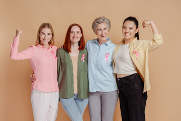 Wall Mural - Portrait smiling strong multiethnic women wearing pink ribbon celebrate recovery isolated on beige background. Health care, support. Breast cancer awareness month 