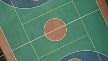 Basketball Court Near Gymnasium. Empty Green Sports Field With White Markings And Hoops Surrounded By Pavement And Trees Upper View Camera Rotates