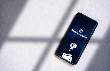 Top view of smartphone transfering money online on screen. Concept of financial transactions with mobile devices. Smartphone screen displaying money transfer confirmation.