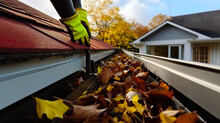 Close-up Of A Man's Hand In A Green Glove Is Cleaning The Roof Of The House From Fallen Leaves.