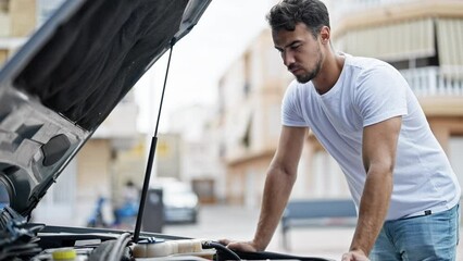 Wall Mural - Young hispanic man looking motor car with worried expression at street