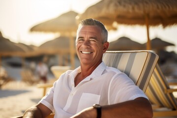 Wall Mural - Portrait of smiling senior man sitting in deck chair on the beach