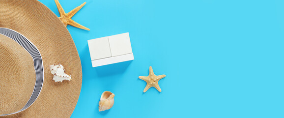Wooden calendar on a blue background with summer accessories, top view. Holidays in summer. Perpetual calendar, hat, shells and starfish. Mockup for entering the date and month. Empty white cubes
