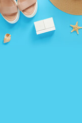 Wooden calendar on a blue background with summer accessories, top view. Holidays in summer. Perpetual calendar, hat, sandals and starfish. Mockup for entering the date and month. Empty white cubes