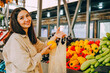 © dvulikaia - Young beautiful brunette woman choosing pepper on local farmers market.