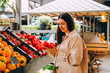 © dvulikaia - Beautiful young woman choosing tomatoes on local farmer's market.