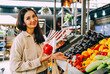 © dvulikaia - Young beautiful brunette woman choosing pepper on local farmers market.