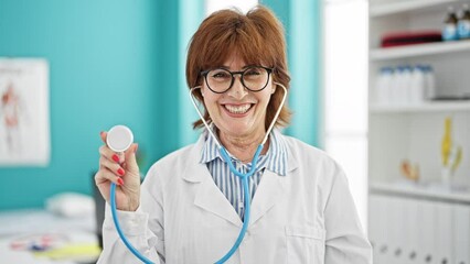 Wall Mural - Middle age woman doctor smiling confident holding stethoscope at clinic