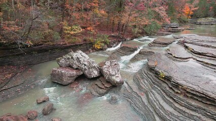 Wall Mural - Mountain waterfalls flow over rocks as a cascade during autumn with fall colored forest tree leaves near the stream     