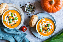 Pumpkin And Tomato Cream Soup Topped With Sour Cream, Pumpkin Seeds And Basil
