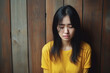 © Anastasiia - Sadness Asian Woman In Yellow Polo Shirt On Wooden Plank Background