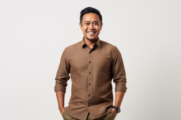 Wall Mural - Portrait of a smiling young asian man standing against white background