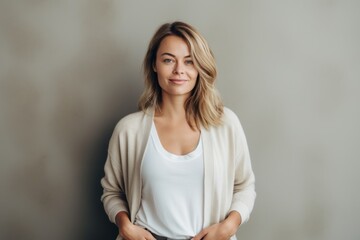 Portrait of a beautiful blonde woman in a white sweater on a gray background