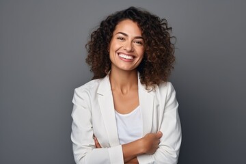 Portrait of a smiling young businesswoman standing isolated over grey background