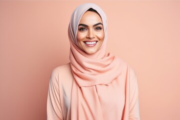 Wall Mural - smiling muslim woman in hijab looking at camera isolated on pink