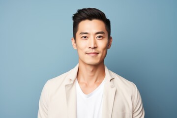 Wall Mural - Portrait of a handsome young asian man on a blue background