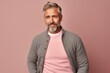 © Anne-Marie Albrecht - Portrait of handsome mature man with grey hair and beard, dressed casually, posing against pink background.
