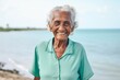 © Leon Waltz - Medium shot portrait of a 100-year-old elderly Nigerian woman in a beach background wearing a sporty polo shirt