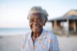 © Leon Waltz - Medium shot portrait of a 100-year-old elderly Nigerian woman in a beach background wearing a sporty polo shirt