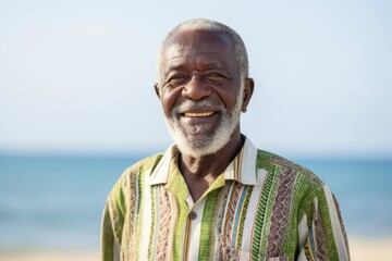 Wall Mural - Lifestyle portrait of a 100-year-old elderly Nigerian man in a beach background wearing a chic cardigan