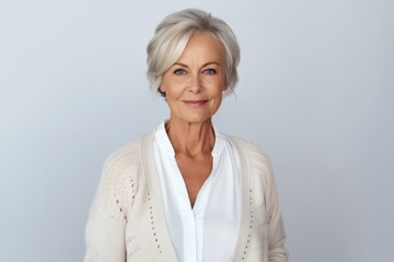 Medium shot portrait of a Russian woman in her 60s in a white background wearing a chic cardigan