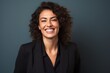 © Leon Waltz - Portrait of a smiling young businesswoman with curly hair against grey background
