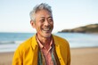 © Eber Braun - Portrait of happy senior man smiling at camera while standing on beach