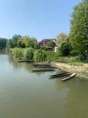 Sticker - a river with boats on the bank of it, and trees around