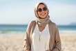 © Eber Braun - Portrait of a smiling young woman wearing sunglasses and hijab on the beach