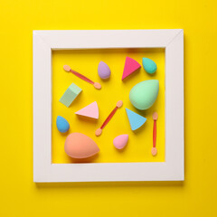 Wall Mural - Make-up sponges, cosmetic blenders and applicators for makeup in frame on yellow background. Beauty products. Top view. Flat lay