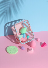 Wall Mural - Makeup sponges blenders in supermarket basket on a pink blue background with palm leaf shadow. Beauty concept. Creative layout, minimalism