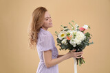 Fototapeta Tulipany - Beautiful woman with bouquet of flowers on beige background