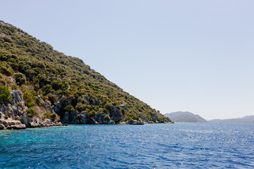 Beautiful view of the Mediterranean Sea with yachts. Picturesque landscape of blue ocean and green mountains on a sunny summer day. The sunken city of Kekova, Türkiye - 28 July 2023