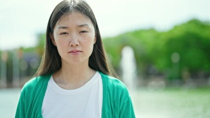 Sticker - Young chinese woman standing with serious expression at park