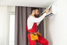 Professional Technician Maintaining Modern Air Conditioner Indoors. Space For Text