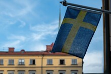Swedish Flag Is Displayed On The Exterior Wall Of A Brick Building On A Sunny Day