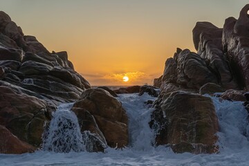 Canvas Print - Scenic view of a waterfall and rocky outcrop on the horizon at sunset in Yallingup, Australia