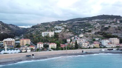 Wall Mural - Landscape footage of Ospedaletti Comune houses by  Ligurian Sea with cloudy sky in Italy