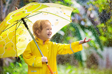 Child Playing In The Rain. Kid With Umbrella.