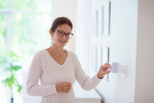 Woman Adjusting Thermostat. Central Heating.