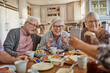 © Marko Geber - Senior people having breakfast and using a smart phone at home in a nordic styled kitchen
