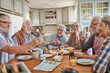 © Marko Geber - Senior people having breakfast and using a smart phone at home in a nordic styled kitchen