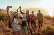 © Marko Geber - Diverse group of young people hiking and taking a moment to take a selfie with a smart phone overlooking a beautiful sunset and ocean