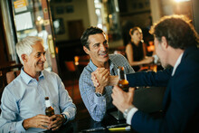 Group Of Businessmen Having A Beer And Celebrating After Work In A Cafe Bar