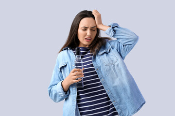 Sticker - Young woman with bottle of vodka on light background