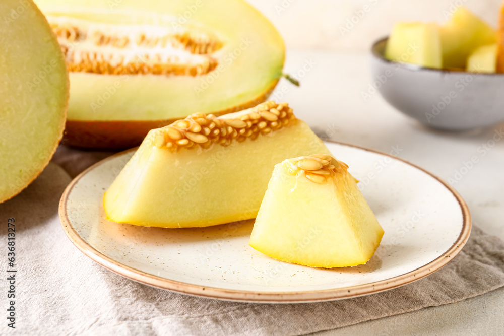 Plate with pieces of sweet melon on white background