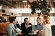 © Geber86 - Group of business people having coffee and talking in a cafe decorated for the christmas and new year holidays