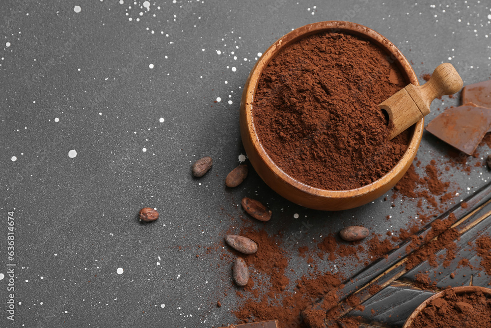 Bowl with cocoa powder and beans on black background