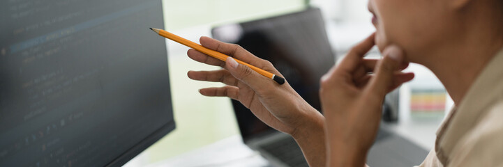 Wall Mural - Developer programmer holds pencil and checking code on monitor while programming to developing web