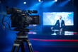 Professional TV Camera Standing in Live News Studio with Anchor seen in Small Display. Unfocused TV Broadcasting Channel with Presenter, Newscaster Talking. Mock-up Television Channel Newsroom Set